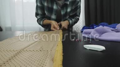 在裁缝`工作室里用剪刀剪出布料。 妇女设计和创造服装在车间工作室。 缝纫车间